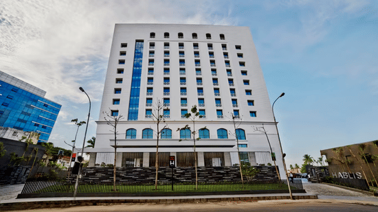 Daytime facade view of Hablis Hotel in Chennai with street lights in front of it and blue sky in the background. One of the best Corporate Team Outing Places in Chennai.