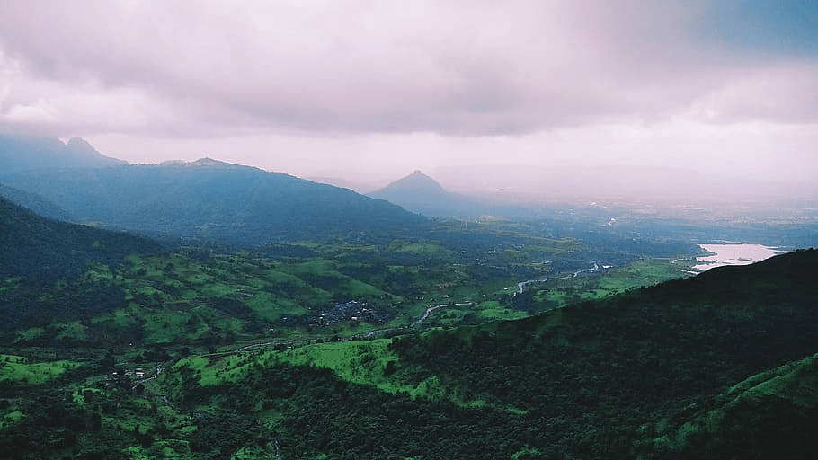 image of a beautiful landscape with a thick green blanket of vegetation over the mountains with a cloudy sky in the background in Lonavala.