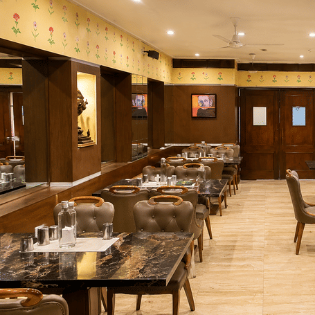 Super Snax restaurant with granite-topped tables, upholstered chairs, floral wall motifs, patterned panels and a tiled floor at MAYFAIR Garden, Rourkela.