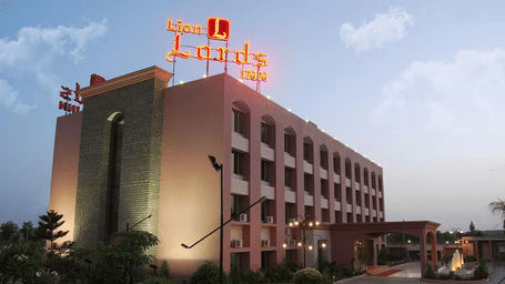 A large hotel building with a red sign on the roof at sunset.