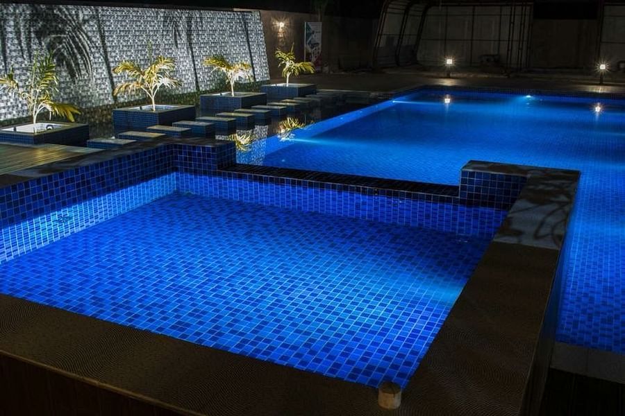 The distinctly blue waters of the swimming pool light up at night - Wedlock Greens Hotel Resorts Dhanbad
