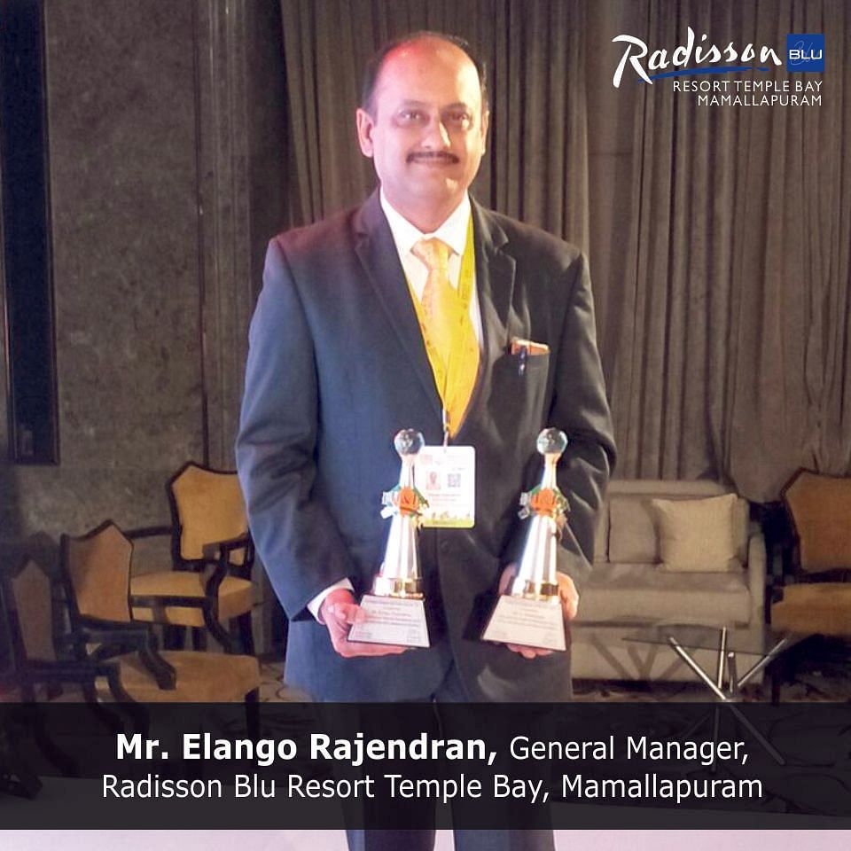 Mr. Elango Rajendran-General Manager-Radisson Blue Resort Temple Bay-Mamallapuram posing with two awards in each of his hands.