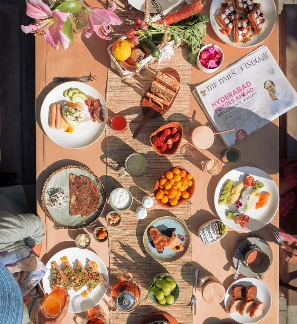 Overhead view of a wooden table filled with various dishes and drinks at Karma Chalets.