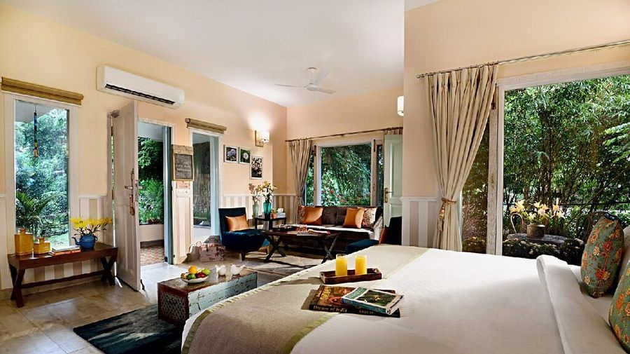 Spacious bedroom with a large bed, seating area, glass doors, and greenery visible outside at Karma Chalets.