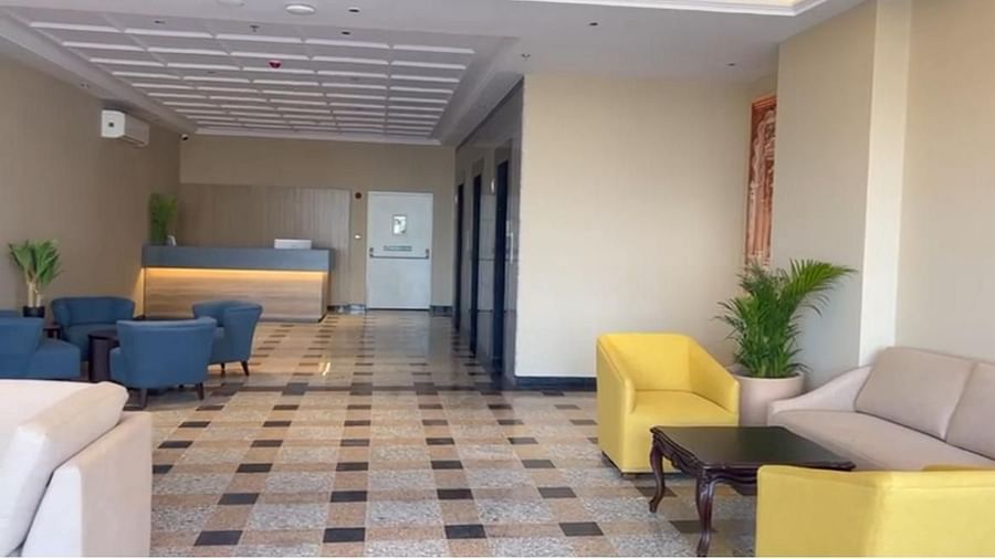 A view of the reception area with furniture on both sides, a table in front, and a desk at the farthest end.