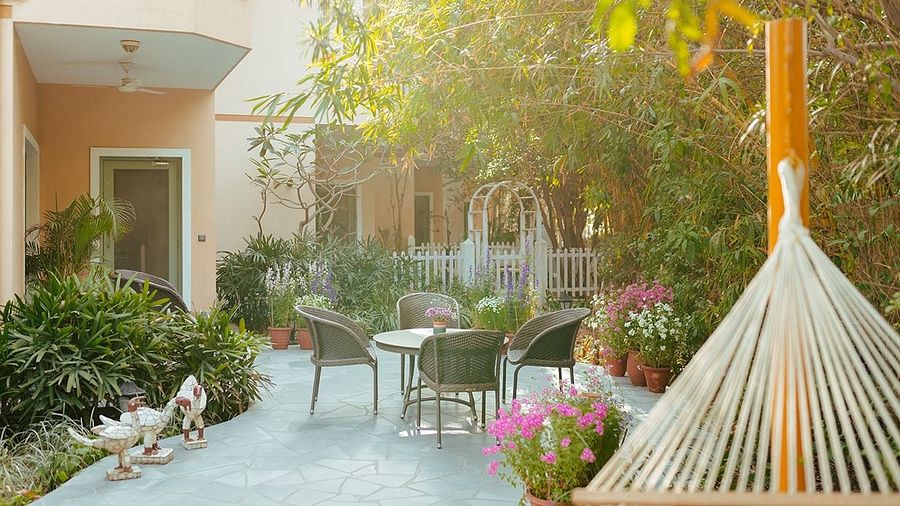 Outdoor seating at Karma Chalets with a hammock, round table, and plants surrounding a small courtyard.