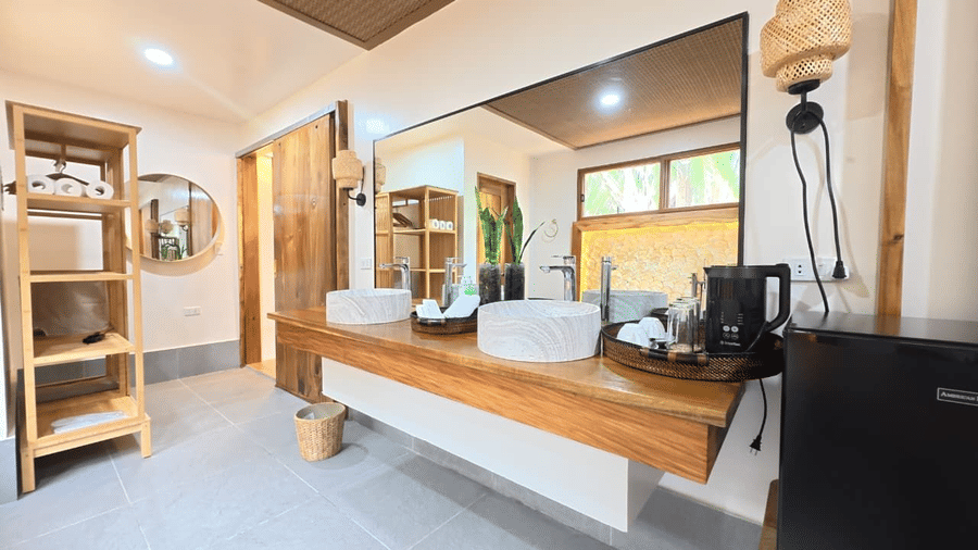 Flower Island Resort | A bathroom with a stone sink, a mirror, and wooden storage spaces.
