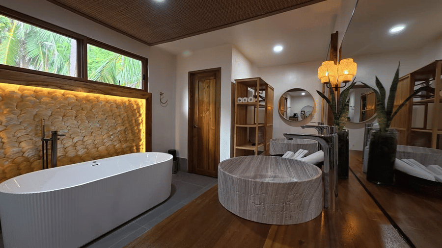 Flower Island Resort | A bathroom with a bathtub, windows, and a stone sink. 