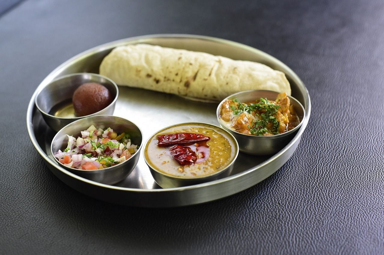 a thali with flatbread and side dishes in smaller bowls