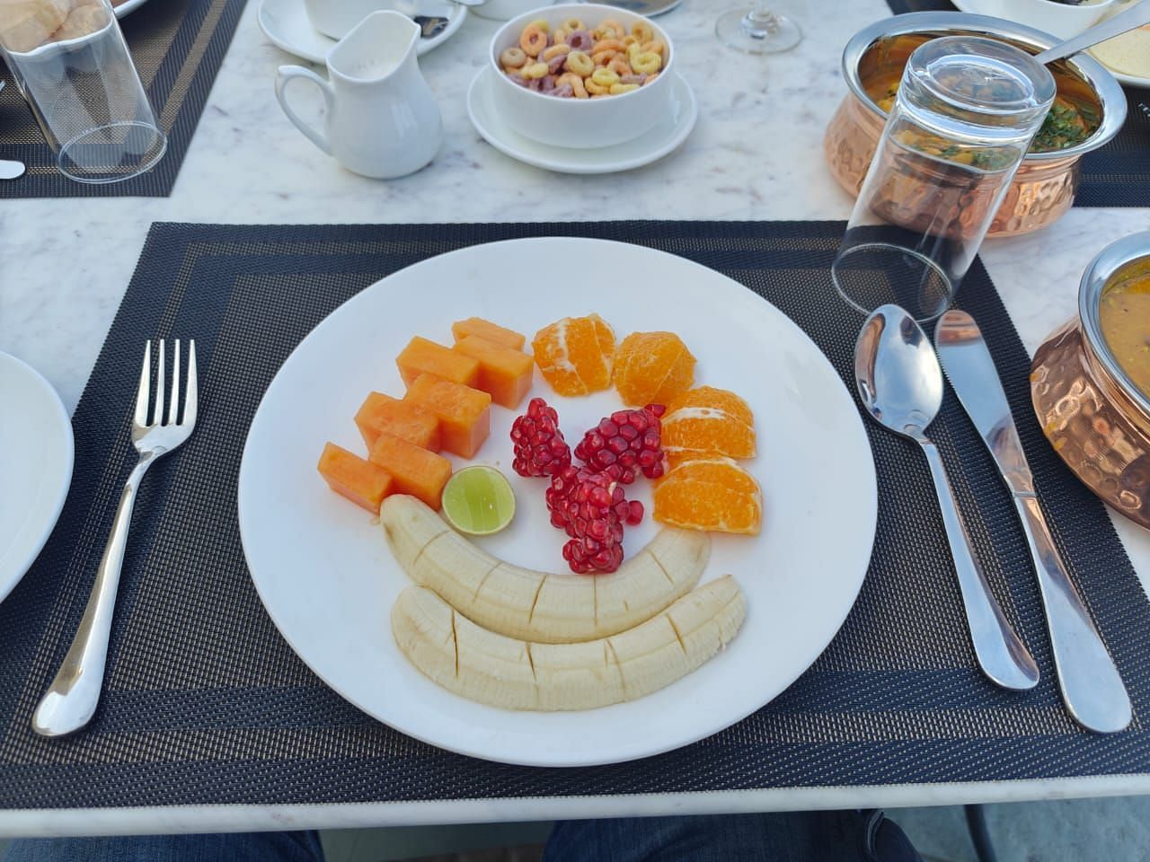A plate with freshly cut fruits and cutlery on the side at KURJA Jawai.
