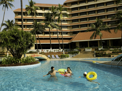 The Retreat Hotel and Convention Centre exterior view showing the large swimming pool with guests relaxing, surrounded by landscaped greenery and the hotel building in the background.