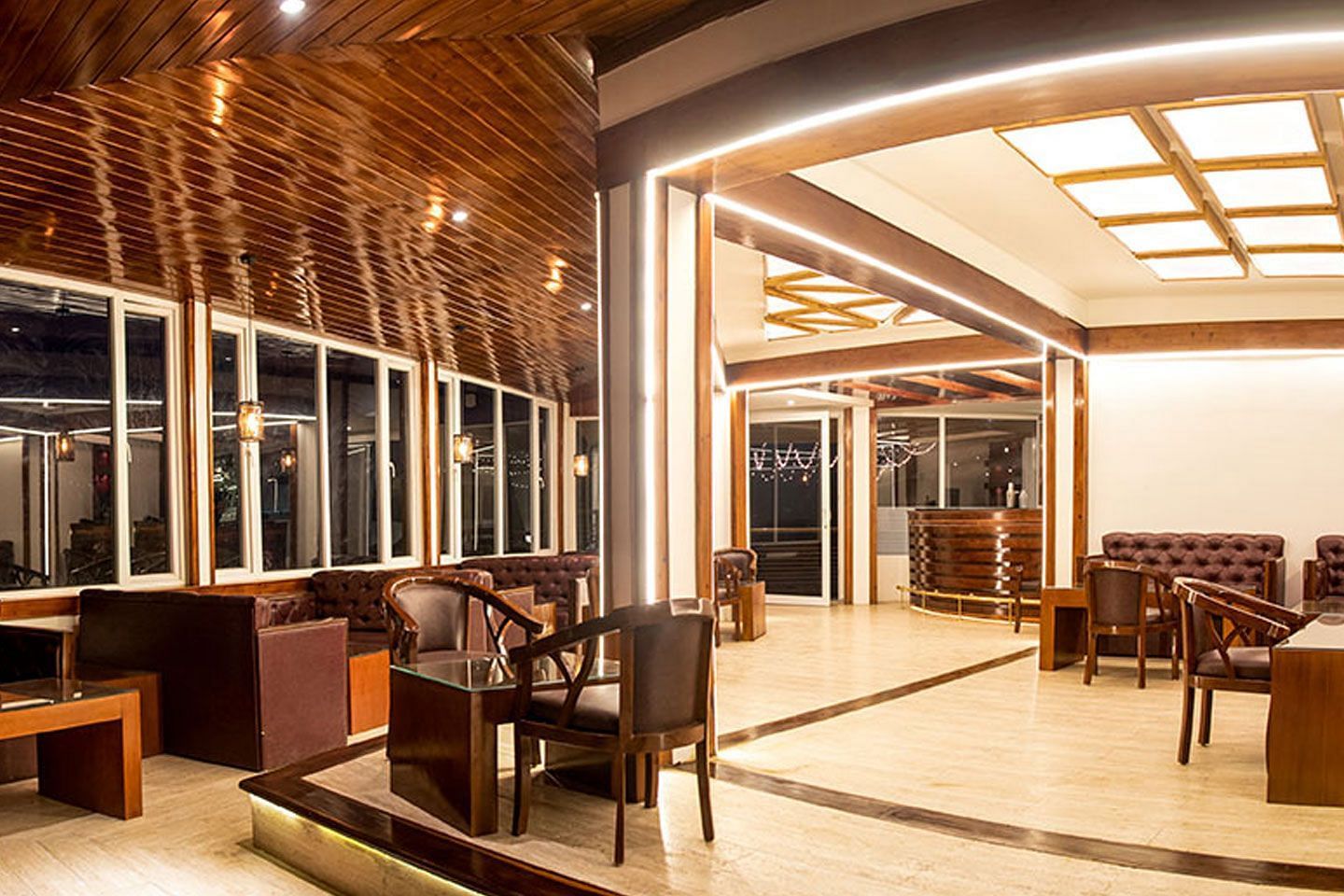 a wide angle shot of a bar featuring leather couches, lit by warm lighting - Summit North Star, Gangtok