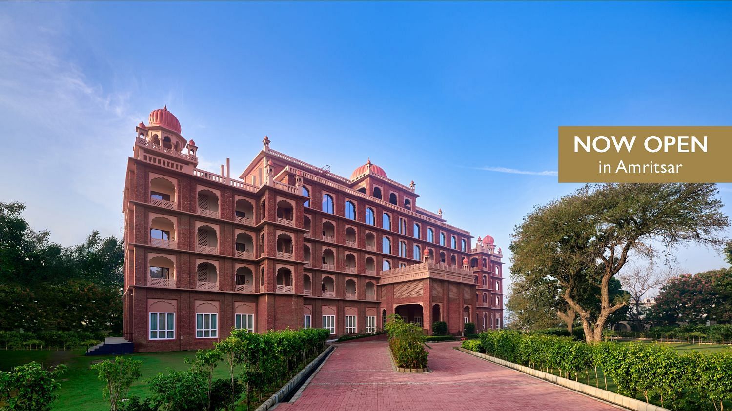 The pathway leading to our hotel in Amristar surrounded by trees and a text box to the right side with the text Now open in Amristar - Sarovar Premiere Amritsar