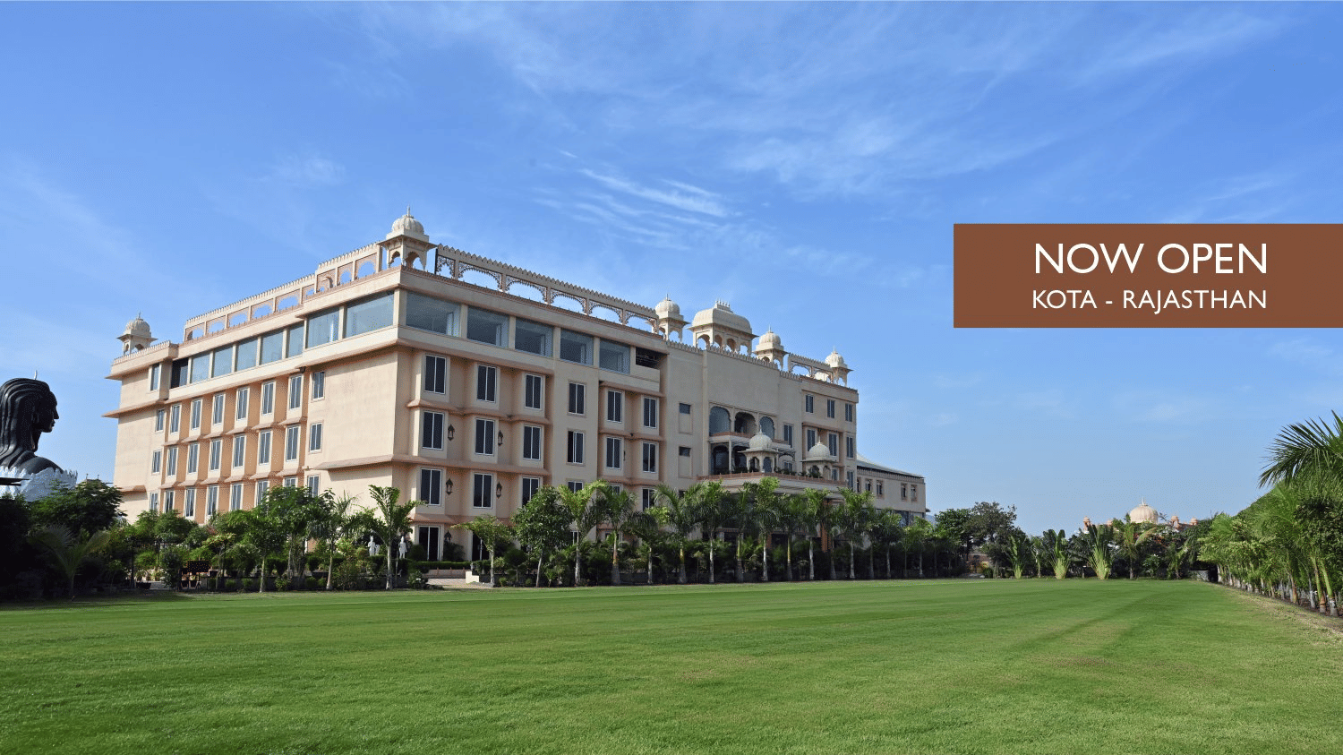 Web banner of Mukundra Sarovar Premiere, Kota, featuring the hotel's themed facade, vast & manicured lawn, and a card on one side with the words 'Now Open' & 'Kota - Premiere'.