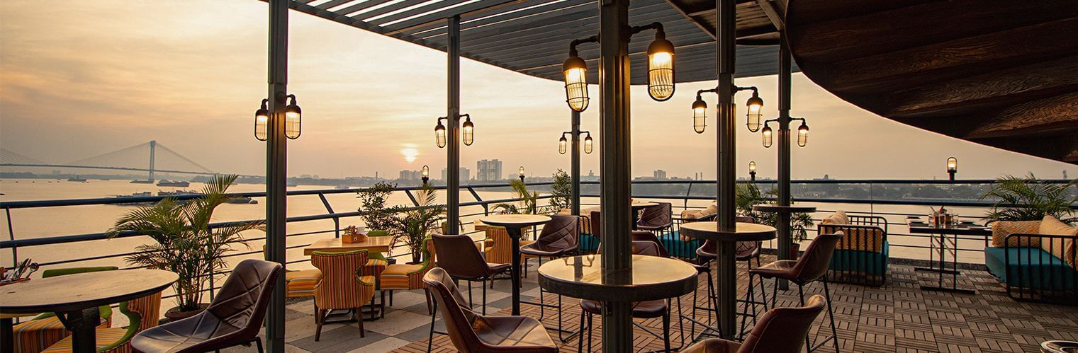 Rooftop cafe at Polo Floatel Kolkata with a canopy, seating area, and a river view.