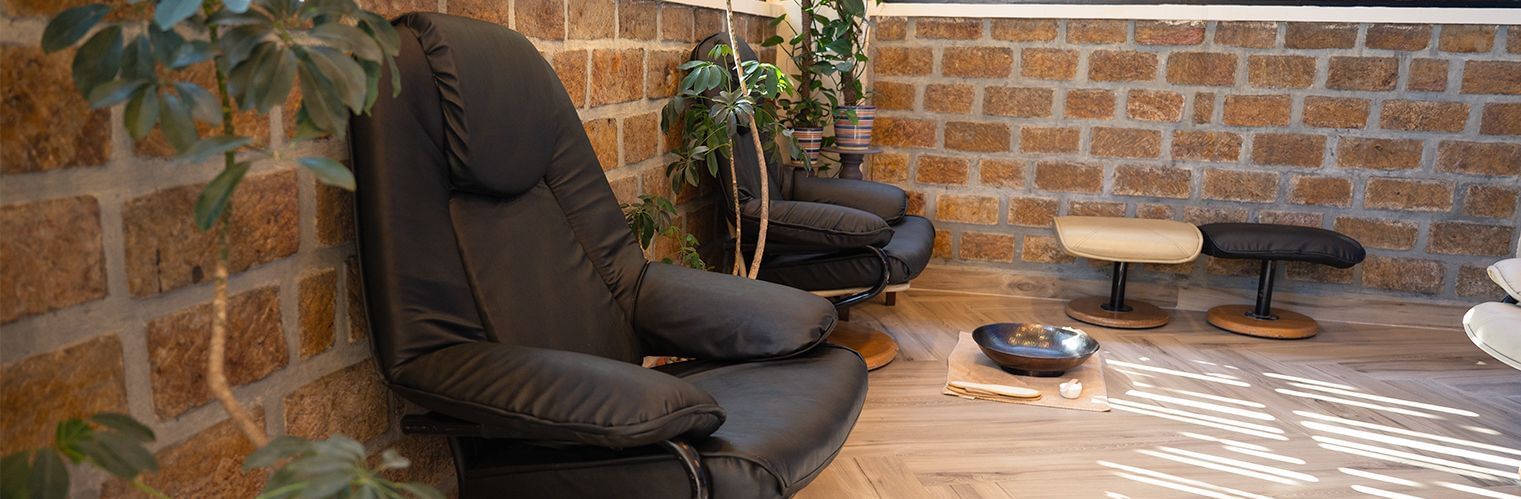 An interior image from Polo Resort Cherrapunjee showing 2 chairs and a small table.