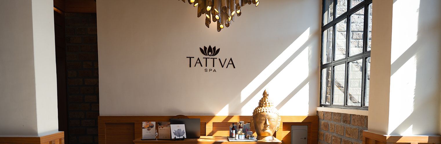 The interior of the Polo Resort Cherrapunjee lobby with a chandelier and a sign that reads 'Tattva'.