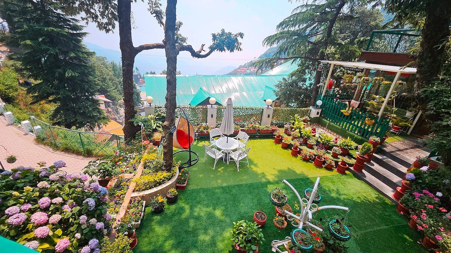 Charming garden area with vibrant flowers, seating arrangements, and a scenic hillside view surrounded by lush greenery -Mongas Hotel & Resort, Dalhousie