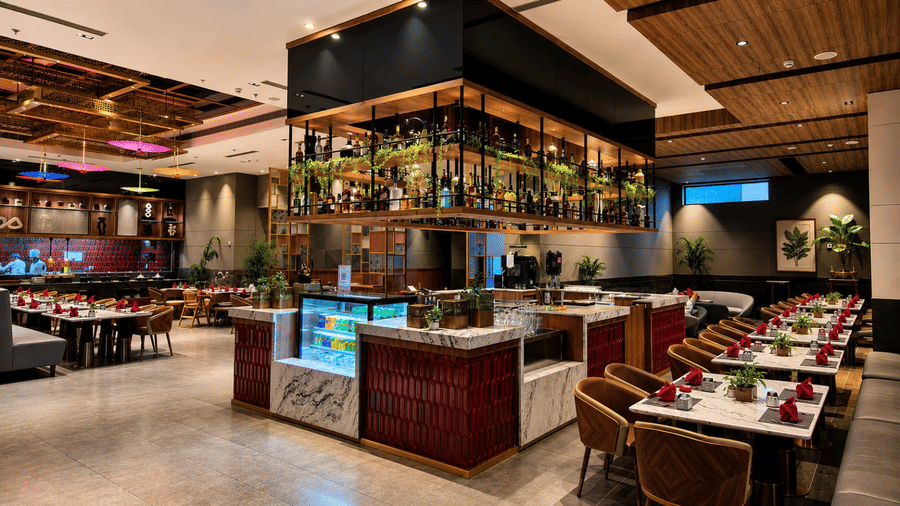 Vibrant and lively specialty restaurant with open kitchen counters, colourful décor, display shelving, and mood-lit dining tables.