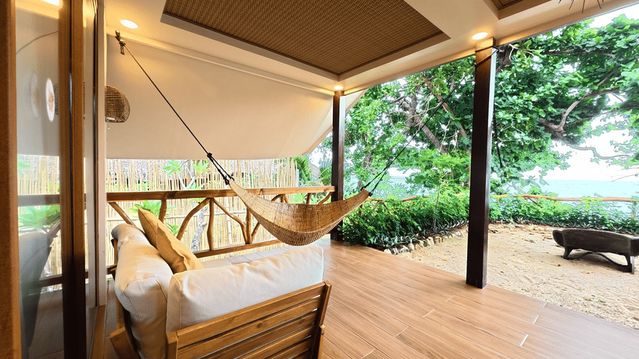 A seating area with a sofa, pillows, a table, and plants. | Flower Island Resort