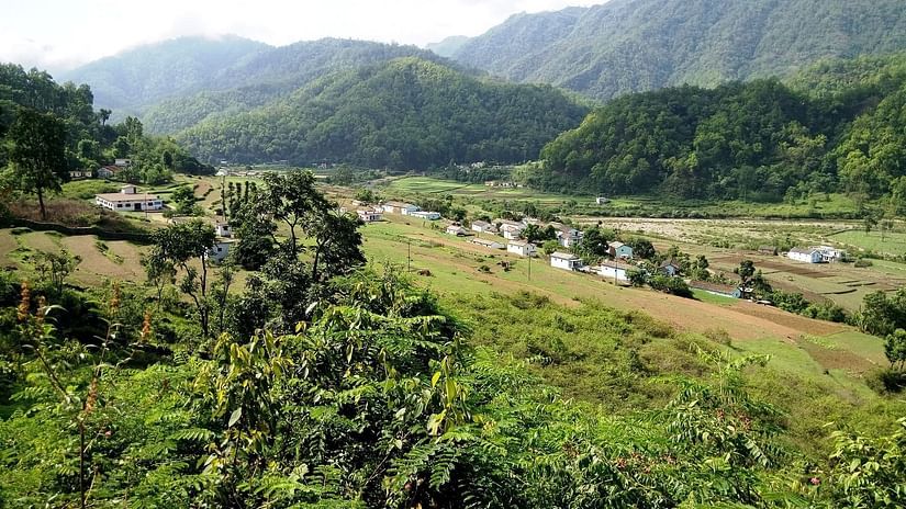 Few building surrounded by lush greenery and mountains in the background