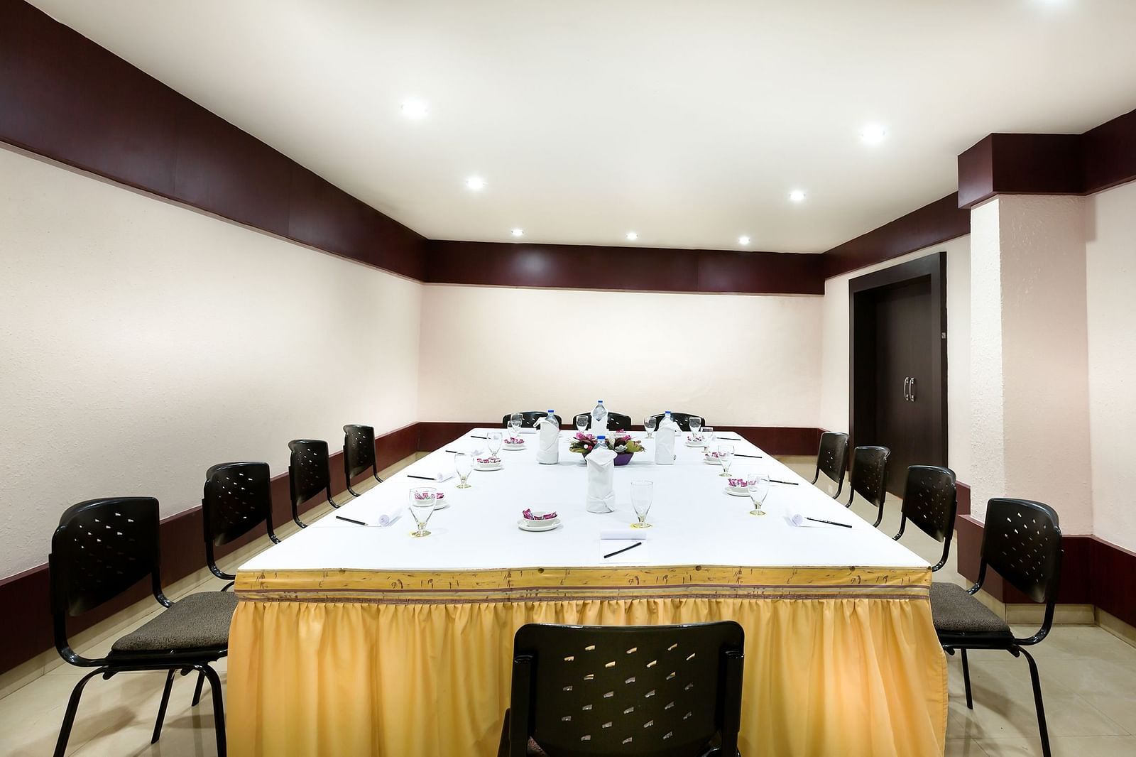 A view of the conference hall with a white table surrounded by chairs at Regency Tuticorin by GRT Hotels.