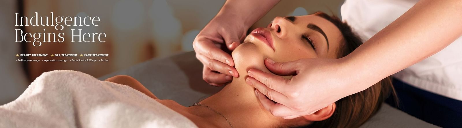A woman receiving a relaxing facial massage at a luxury spa, with the text Indulgence Begins Here in the background.