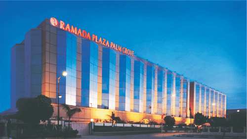 Facade of Hotel Ramada Plaza Palm Grove, Juhu, Mumbai, during twilight hour with the lights on.
