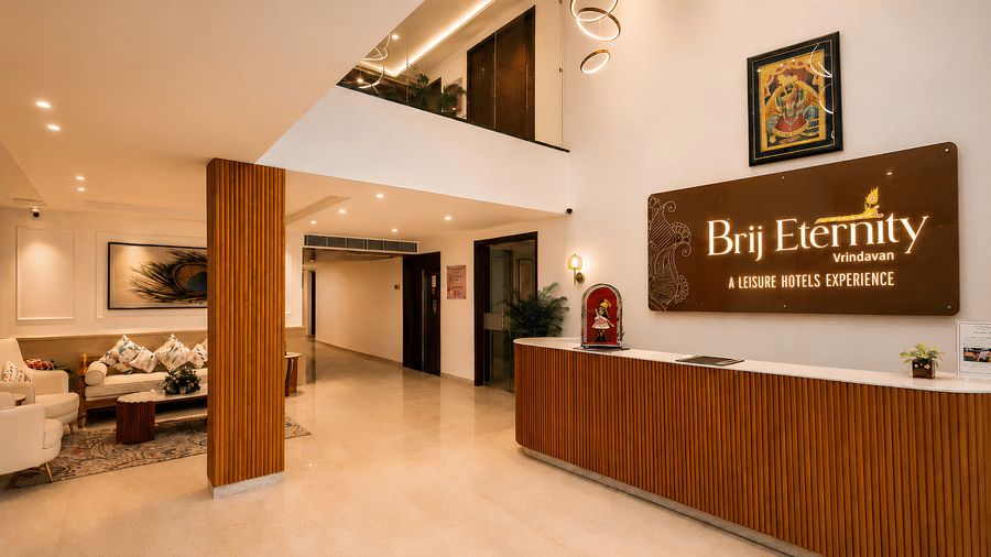 Reception lobby at Bel Eternity Hotel, featuring a wooden front desk, a double-height ceiling, and modern interiors.