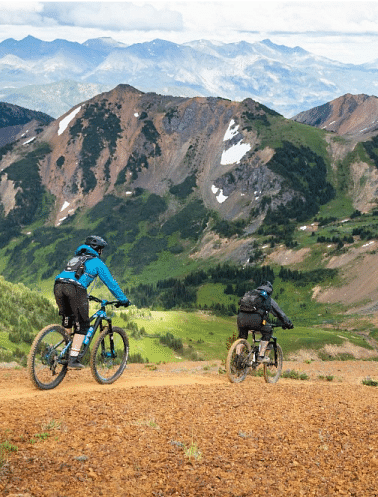 People cycling through a grassland with mountains in the backdrop
