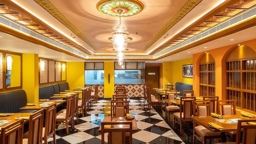 image of the dining area of the chettinad stories fwaturing white and black tiles in the ground at hotel aadithya in chennai