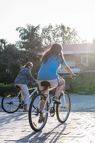 A woman and a child riding bicycles on a sunlit pavement at Karma Chalets.