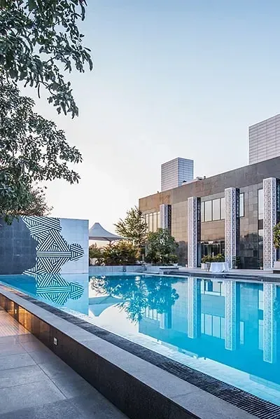 A long outdoor swimming pool beside modern white buildings at Karma Chalets.