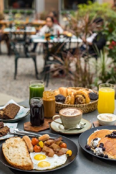 Breakfast spread on an outdoor table at Karma Chalets with eggs, toast, baked goods, juice, and fruit.