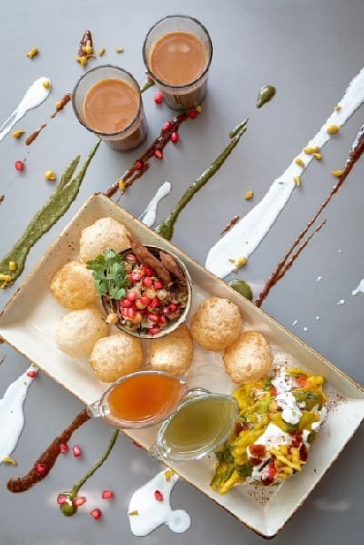 Top view of assorted Indian snacks and tea served on a white tray with sauces at Karma Chalets.