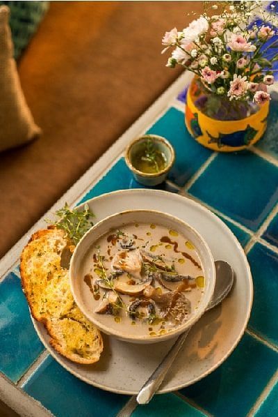 Bowl of soup with bread and a drink placed on a blue tiled table at Karma Chalets.