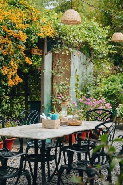 Karma Chalets garden dining space with black chairs, tables, and orange flowers hanging overhead.