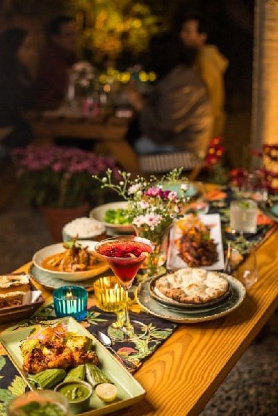 Table at Karma Chalets with a variety of plated dishes including salad, grilled meats, and desserts in a low-lit dining setup.