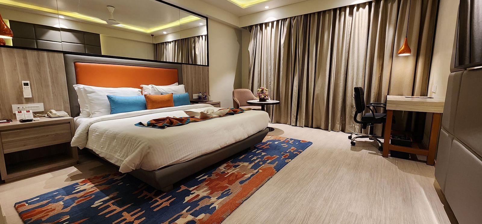 Contemporary room with bright decor, patterned carpet, and a bed facing a flat-screen television.