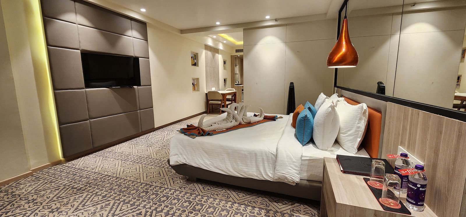 Elegant hotel room with a king-sized bed, bedside tables, modern wall art, and a mounted flat-screen TV.