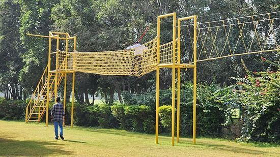 An image of the obstacle course where a man is crossing it and a man is standing below and watching - Karma Lakelands, Gurgaon