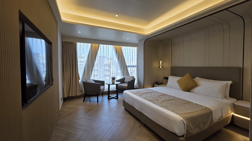 Premium room at Dragonfly Hotel – The Art Hotel with large bed, white linens, beige throw blanket, yellow accent pillow, wall?mounted television, seating area near window, and recessed ceiling lights.