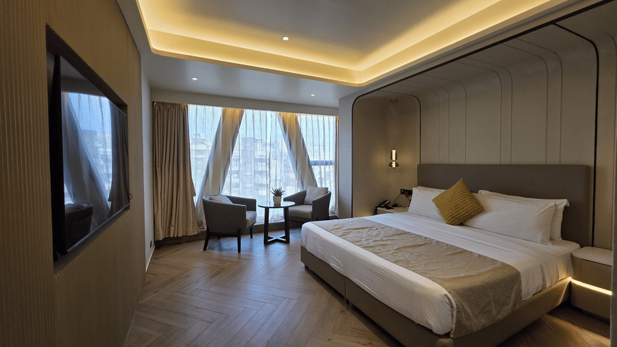 Premium room at Dragonfly Hotel – The Art Hotel with large bed, white linens, beige throw blanket, yellow accent pillow, wall?mounted television, seating area near window, and recessed ceiling lights.