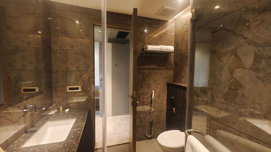 A modern bathroom with a sink, mirror, toilet, and shower area at Pride Resort, Jodhpur, featuring marble finishes.