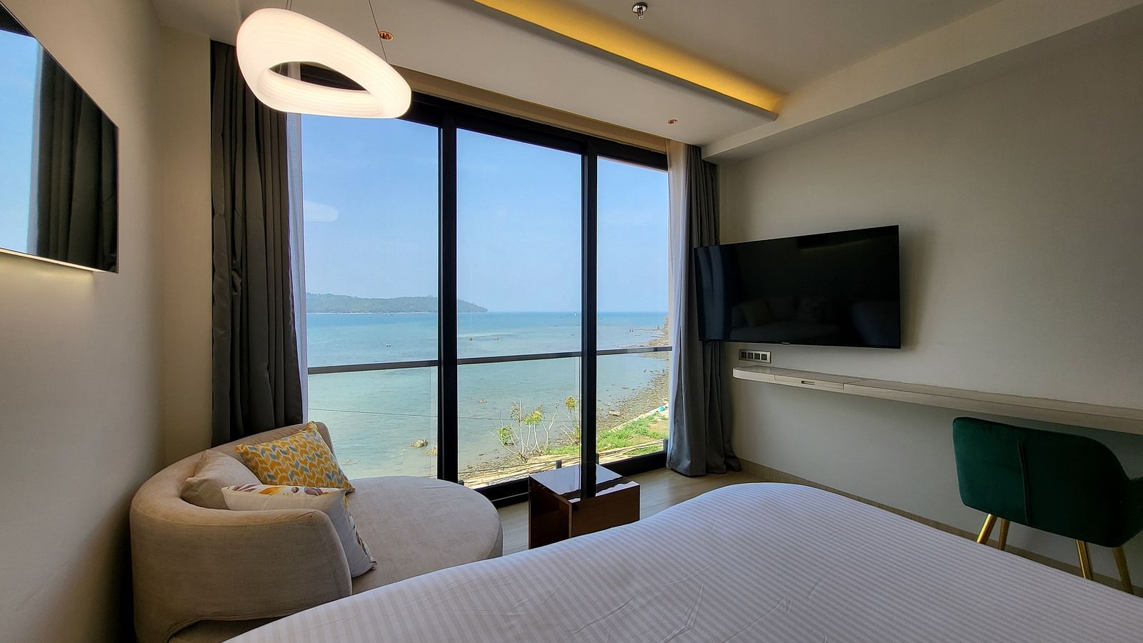 View of half a double bed, a small sofa facing the TV in the 6ix sea view room with Jacuzzi at 6ix Seashore Hotel, Port Blair