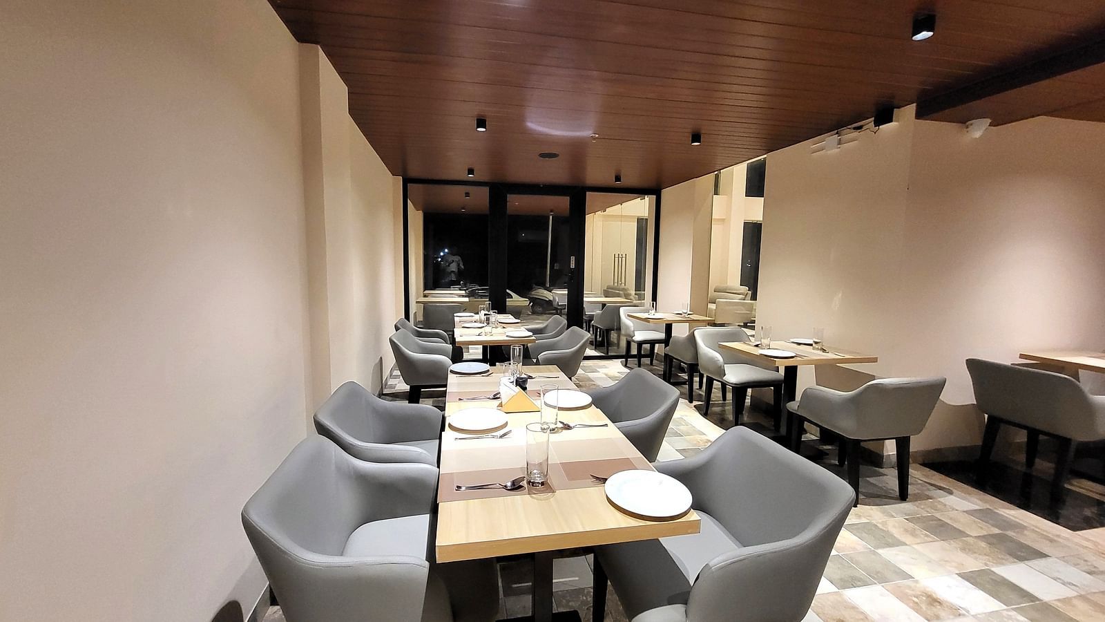 Grey chairs and tables set in a row in 6ix Sea View Restaurant at 6ix Seashore Hotel, Port Blair