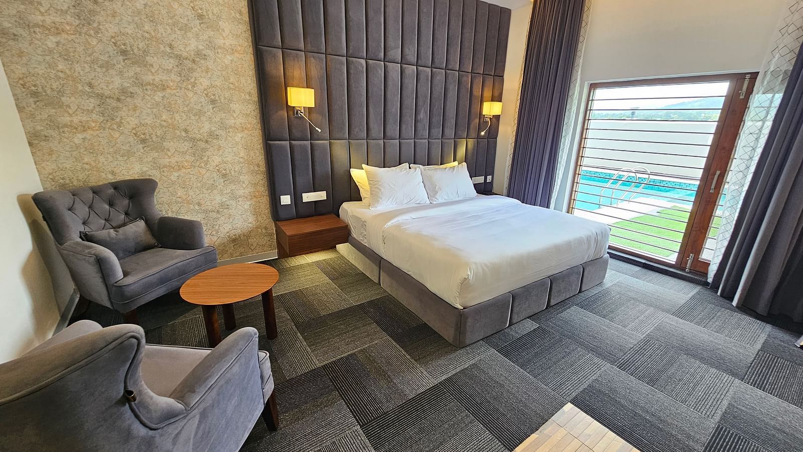 full view image of the premium room at Eminence The Corbett withe a comfortable double bed and huge windows besides it
