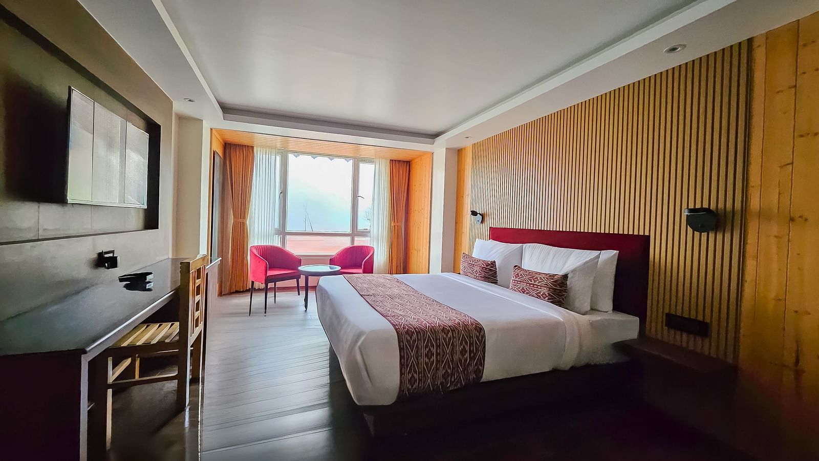 A bedroom with wooden interiors and a false ceiling right above the double bed - Yashshree Lachen