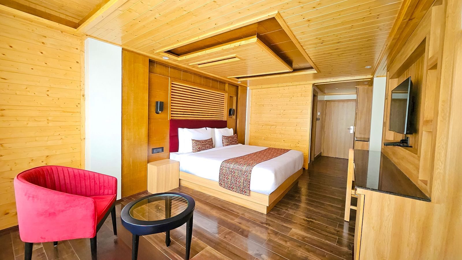 Full view shot of the Premium Room with wooden interiors featuring a double bed right below a wooden false ceiling - Yashshree Lachen