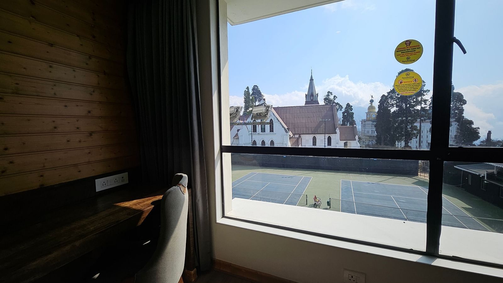 An image of a deluxe room with a work desk, chair and a window overlooking the view - Yashshree Sanderling, Darjeeling